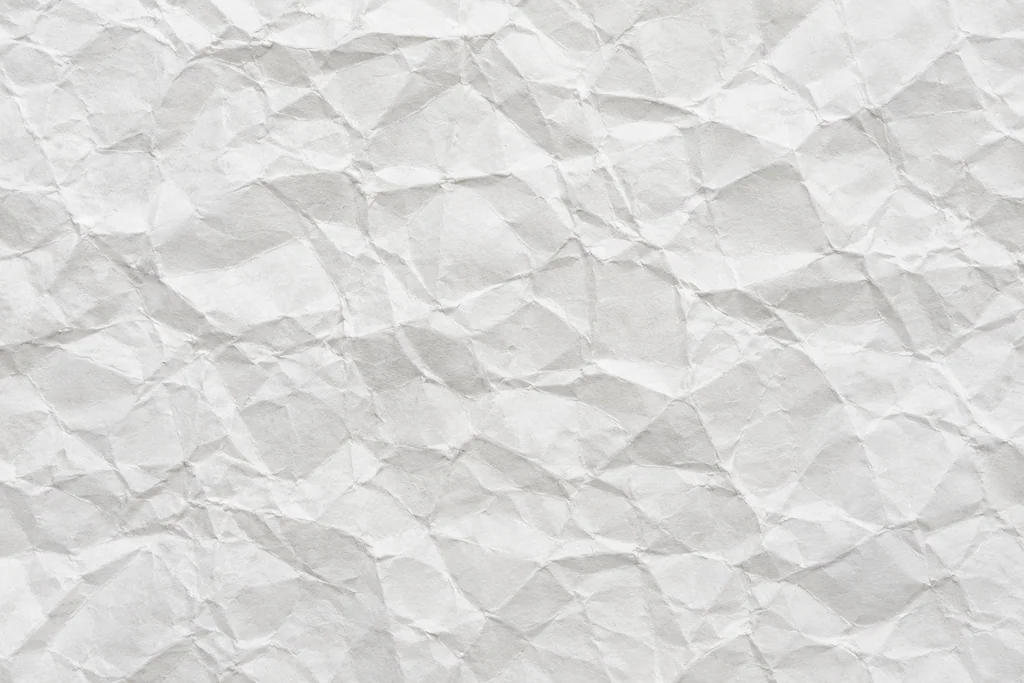 White paper with dense angular creases, raised folds and cool gray shadows